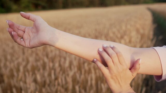 Annoying insects - woman scratches bitten hand from mosquito, bug bites in field