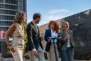 Business people walking and talking outdoors with electric scooter
