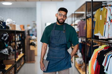 Bicycle shop worker holding tablet and posing in the store