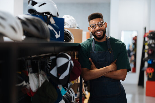 Smiling bicycle shop worker posing with crossed arms