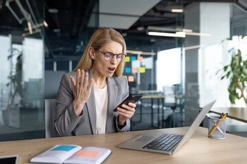 A businesswoman is experiencing a stressful situation while looking at her phone in the office.