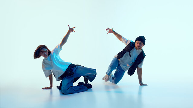 Two hip hop dancers balancing on hands with expressive open-arm gestures and urban styling. Concept of music covers, youth performance, social content, dance advertising visuals.