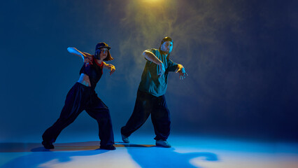 Fototapeta premium Dancers in low pose with theatrical lighting and intense emotional expression. Concept of dance events, creative performance, branding visuals, emotional youth storytelling.