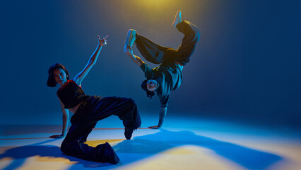 Dancers freezing in intense floor pose with raised limbs and direct eye contact. Concept of...