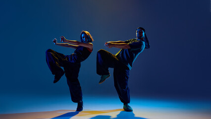 Urban dance pair stepping in sync with calm intensity and mirrored expressive arms. Concept of...