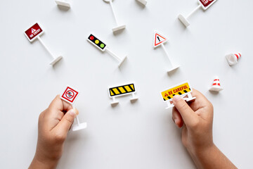 Child hands holding toy road signs on white background