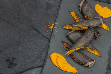 Halloween sweet dessert with traditional decor. Thin black pancakes with pumpkin cream, fall leaves