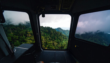 Fototapeta premium Morning aerial view of misty tropical pine forest from inside a low-flying helicopter in the highlands of Southeast Asia