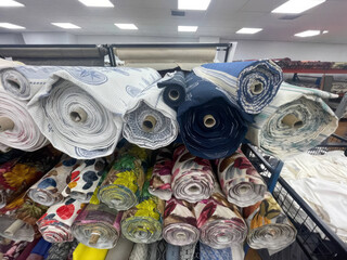 Rolls of vibrant fabric whisper tales of bohemian fests and quirky pattern quests, perfect for eclectic sewing projects