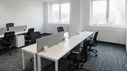 Empty office with ergonomic desks and large windows 
