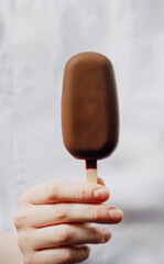 Hand clasping creamy chocolate ice cream bar, indulging in solstitial delight, evoking Sweetest Day and Gelato Festival essence