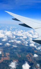 Fototapeta premium Soaring airplane wing skims frothy cumulus clouds, invoking dreams of wanderlust, serendipitous sky-pilgrimage, and Aeropress Day reflections