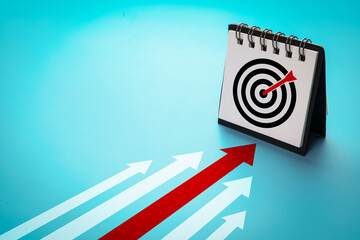 Arrow points to small calendar with a target board symbol on blue background. Concepts of planning, and goal setting for success.