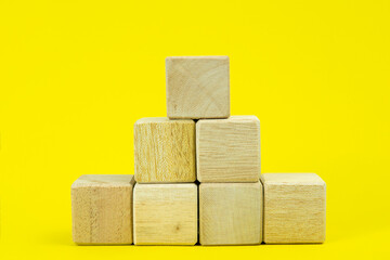 Wooden cube pyramid isolated on yellow background