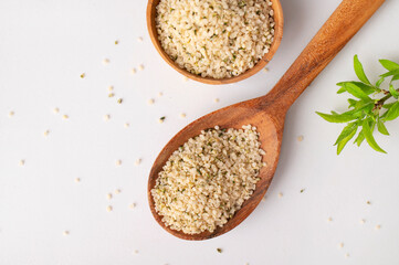 Hemp seeds in wooden spoon and bowls on light background. Superfood, healthy tasty organic hemp...