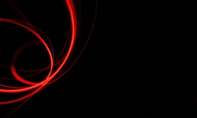Abstract image featuring bright red glowing light trails and curved lines against a deep black background, creating a dynamic visual.