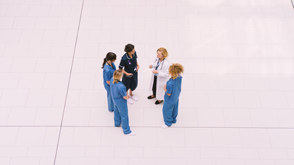 Overhead View Of Female Medical Staff Having Informal Meeting In Lobby Of Modern Hospital Building