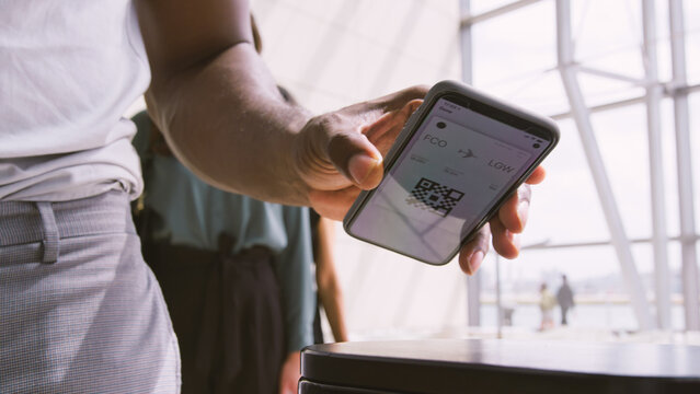 Close Up Of Passengers In Airport Departure Lounge Scanning Digital Boarding Pass On Smart Phone
