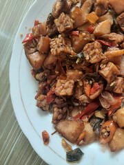 close up of indonesia stir fried tempeh, potatoes, an chili on white plate