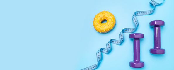 Dumbbells for fitness, sports, measuring tape, sweet donut on blue background. Concept of healthy...
