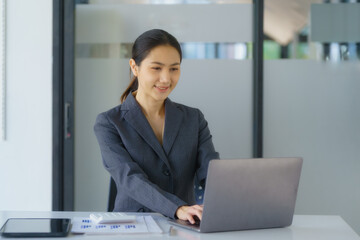 Portrait of an Asian businesswoman working with a laptop computer in her office. Business financial concept.