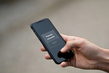 Businessman holding phone with text payment successful on screen display