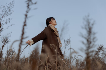 Young woman standing in a field during sunset.