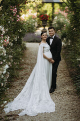 Fototapeta premium An Elegant Wedding Couple Enjoying Their Time in a Beautiful Blooming Garden Together