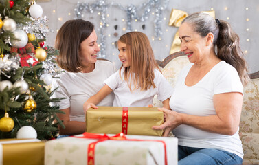 Grandmother mom and daughter holding gift in Christmas interior