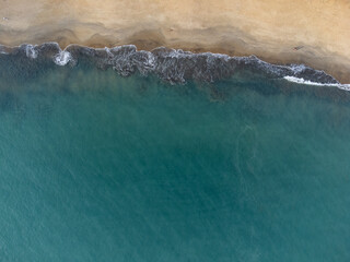 Wonderful tropical beach with blue water and orange sand forming small waves seen from above