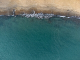 Wonderful tropical beach with blue water and orange sand forming small waves seen from above