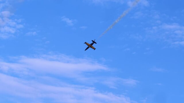 Military aircraft performs steep vertical dive with vapor trail marking its path through bright blue sky, emphasizing precision and speed of modern aerobatic maneuvers during demonstration. Pilot s