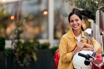 Smiling Woman in Yellow Jacket Sitting on Scooter Outdoors in Urban Environment