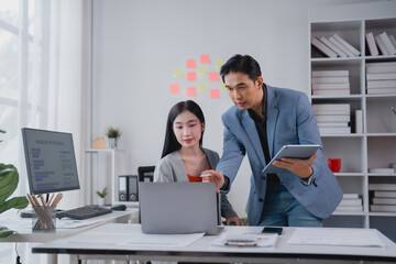 Competent Asian businesspeople engaging in a dynamic discussion over a laptop during an office...