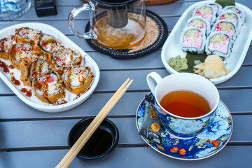 Top View of Sushi with Snow Crab and Hot Salmon, Teapot and Blue Cups on Wooden Table