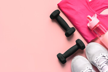 Top view of black dumbbells with T-shirt,sneakers and water bottle with copy space for text. Sport...