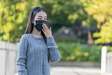 a young asian woman wears protective face mask,suffer from cough,feeling sick while going outside