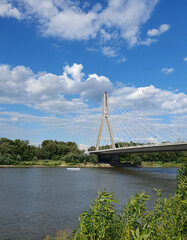 Sunny summer day over the river, clear water brightly reflects the blue sky and fluffy clouds