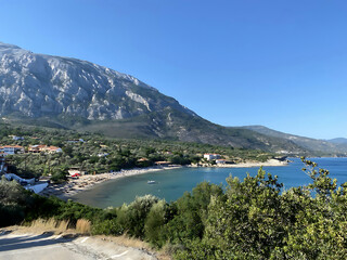 View of the endless blue sea and majestic mountains on a bright summer day. The sun's rays play on the water surface