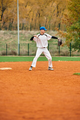 Teenage boy shows skill playing baseball on a colorful autumn field