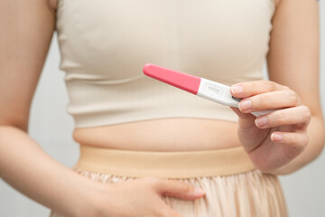 Asian holding pregnancy test for female of ovulation day, fetus, maternity, childbirth, birth control.