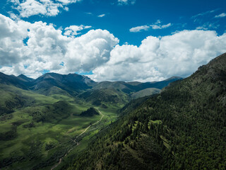 Naklejka premium Aerial view of beautiful high altitude snow capped mountains and forest grassland landscape in China