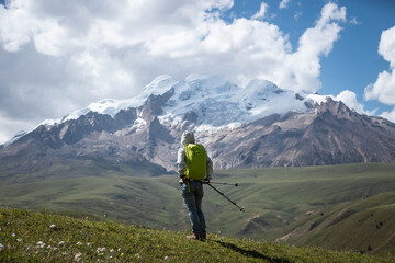 Backpacking woman hiking on grassland enjoy the view of snow capped mountains