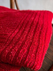 warm knitted clothes on an old wooden chair against a white wall