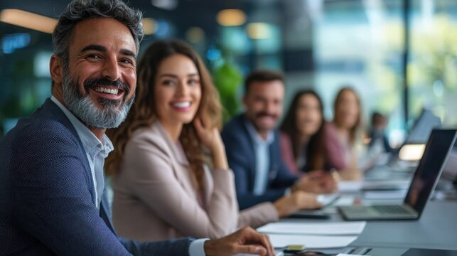 A smiling man and woman in a business meeting with a diverse group of colleagues.