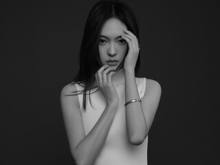Elegant young woman with long hair in thoughtful pose.