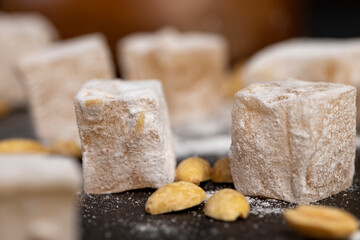 Turkish delight walnut with roasted peanut kernels scattered on a black slate board, sweets made...