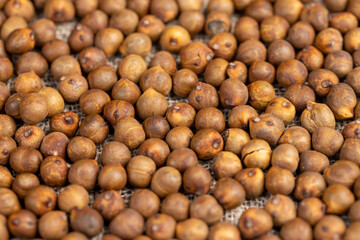 Roasted chickpeas are scattered on the table before cooking, fried but not boiled chickpeas are on the table with a tablecloth.