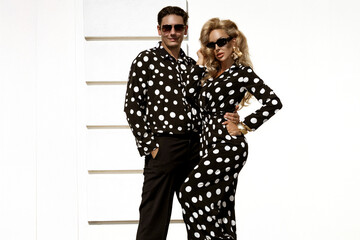 Fototapeta premium Fashionable Female Model and Male Model in Matching Black and White Polka Dot Elegant Outfits Posing Outdoors in Summer Sunny Day. Polka Dot Fashion. Retro