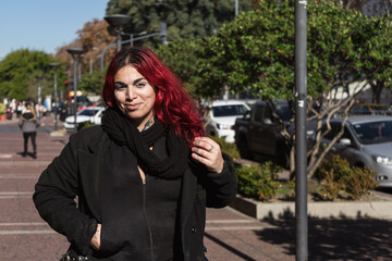 Stylish tattooed woman with red hair walking down the street
